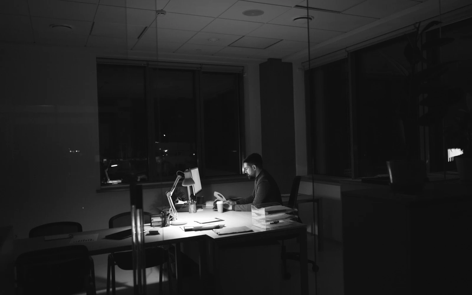 A man working late at a desk in a dark office